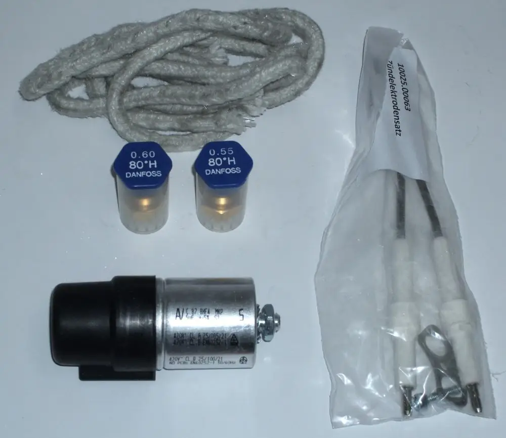 Drei Komponenten eines Daikin Service-Kits: zwei blaue Ventile, ein silberner Zylinder und zwei Zündkerzen in einer transparenten Verpackung, zusätzlich ein graues Kabel.